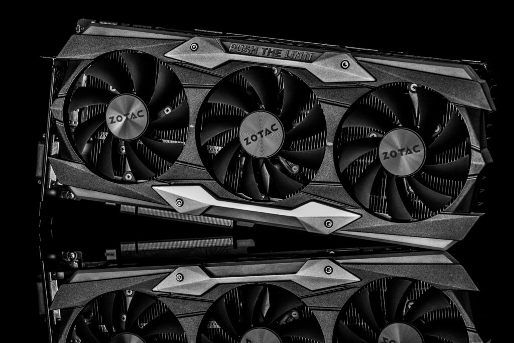 Close-up of a triple-fan graphics card on a dark reflective surface