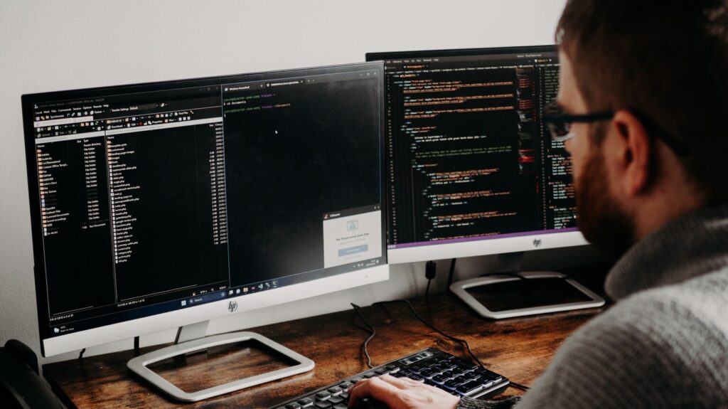 Person troubleshooting at dual monitors Pexels